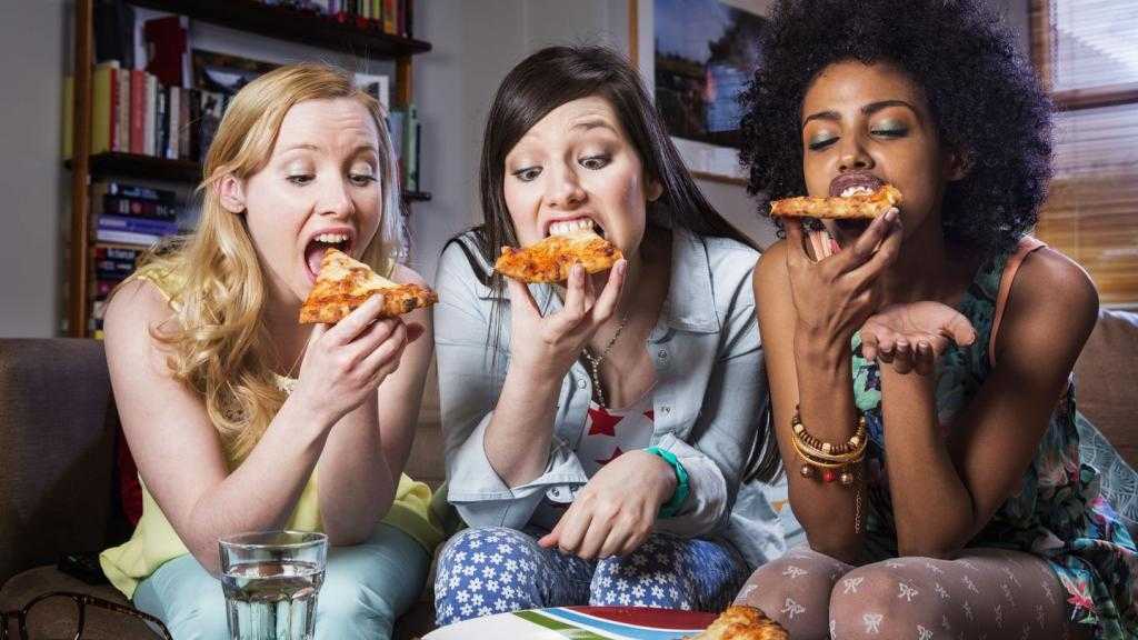 Три девушки едят пиццу.