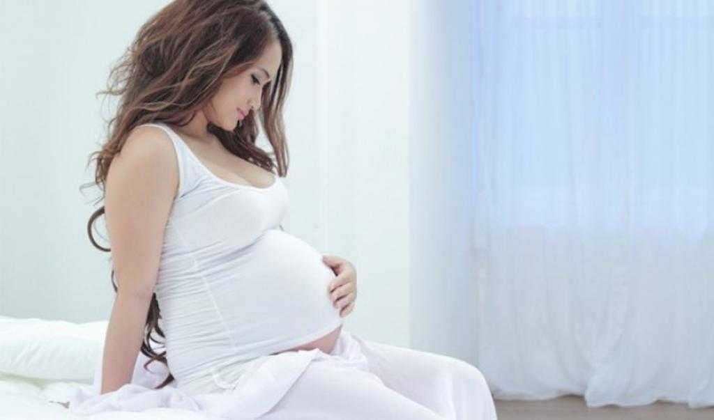 Беременная женщина гладит живот.